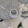 Pendant photographed resting on stones and shells
