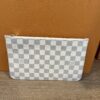 Front of the pochette leaning against the Louis Vuitton box