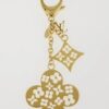 Louis Vuitton Ivy bag charm and keychain in gold tone metal with white enamel monogram flowers, shown hanging