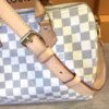 End panel showing the gold strap clip and vachetta trim