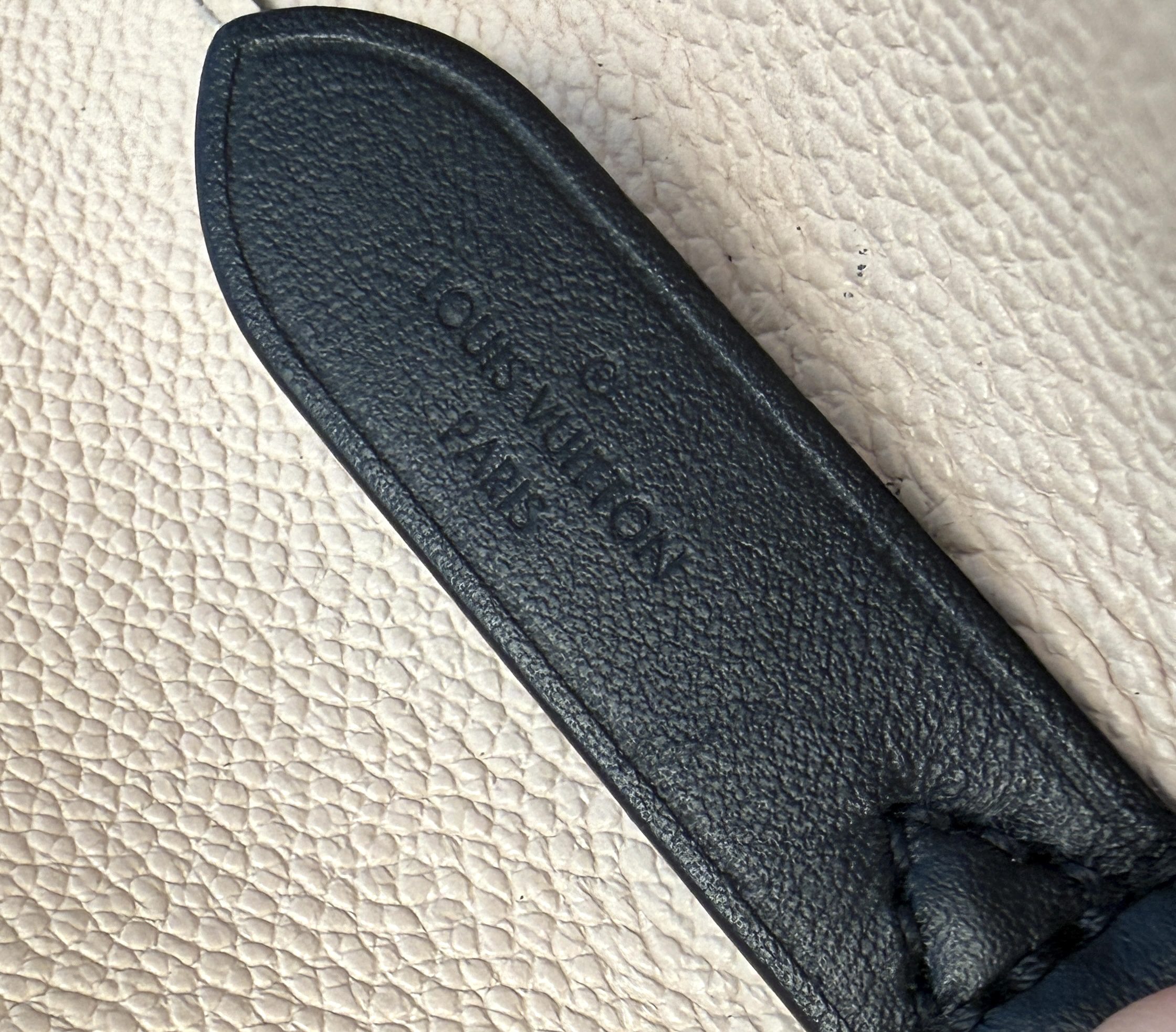 Heat stamp reading LOUIS VUITTON PARIS on the black leather tab